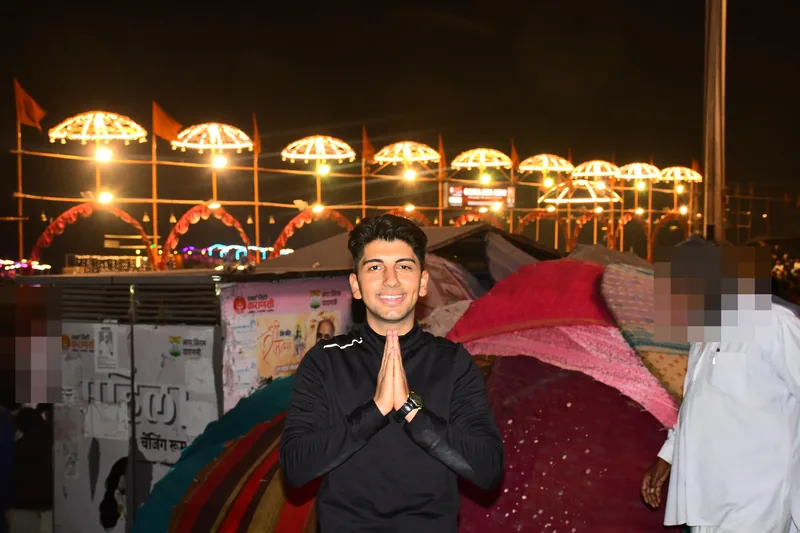 Yiğit ยิ้มพร้อมประนมมือหน้าหลังคาร่มที่สว่างยามค่ำคืนในวาราณสี
