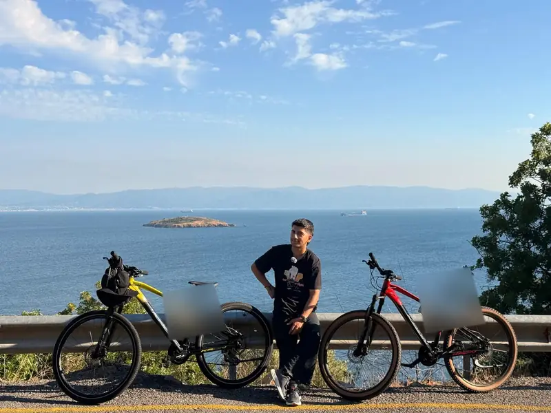 Yiğit, denizin üstünde iki bisikletin arasında