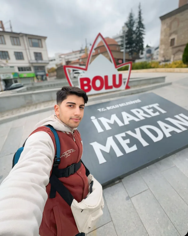 Yiğit ยืนอยู่หน้าป้าย Bolu İmaret Meydanı.