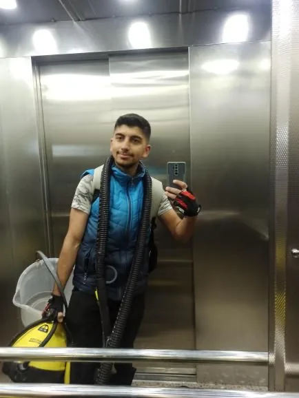 Yiğit with a cleaning machine in an elevator mirror