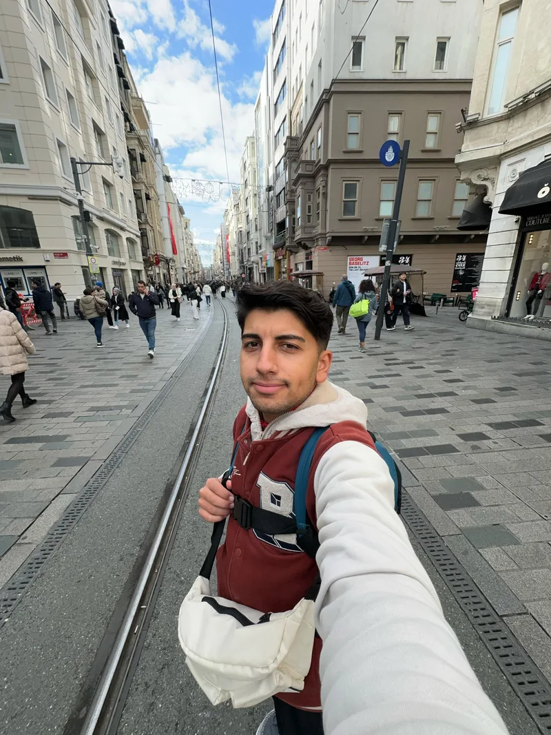 Yiğit ยืนอยู่บนถนนคนเดินที่มีรางรถรางในอิสตันบูล