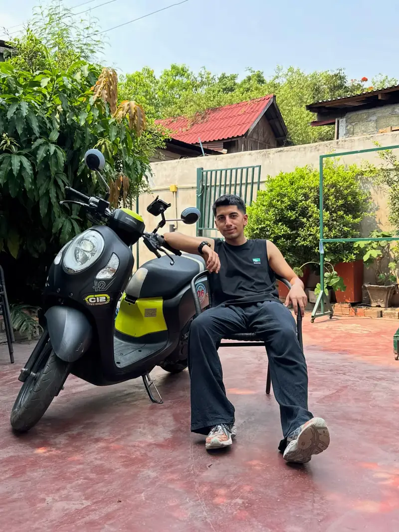 Yiğit, Luang Prabang’da bir avluda, siyah-sarı bir Honda’nın yanında